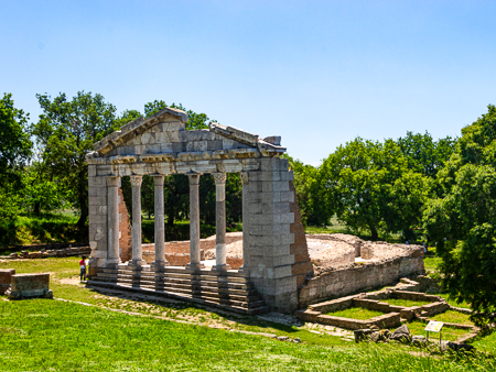 Ancient temple ruins at Apollonia Archaeological Park, Albania, with stone columns and foundations in a green landscape.