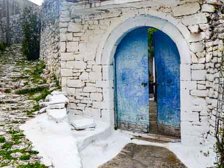 Blue arched wooden door on a stone house in an Albanian village.