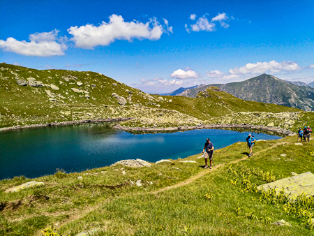 Hikers walking along a mountain path beside a glacial lake in the Dinaric Alps (Albanian Alps).