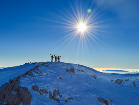 Hikers on a snowy ridge at sunset in the Albanian Alps