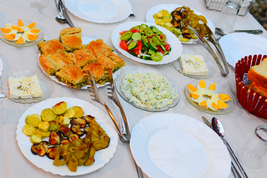 Traditional Albanian meal spread on a table, with byrek, fresh salad, local cheese, eggs, and roasted vegetables.
