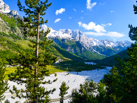 Panoramic view of Valbona Valley with the riverbed and snow-capped Albanian Alps in the distance.
